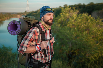 Image showing Young caucasian man with backpack walking on the top of hill