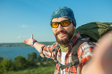 Image showing Young caucasian man with backpack standing on the top of hill