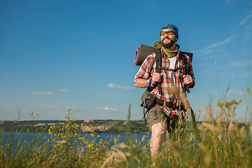 Image showing Young caucasian man with backpack standing on the top of hill