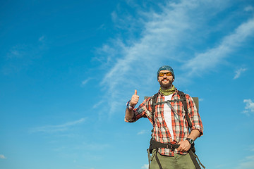 Image showing Young caucasian man with backpack standing on the top of hill