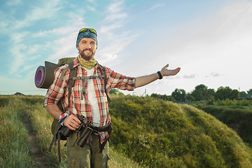 Image showing Young caucasian man with backpack standing on the top of hill