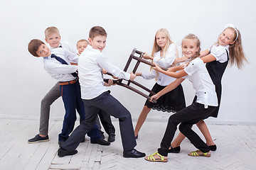 Image showing Kids playing tug of chair - girls versus boys,