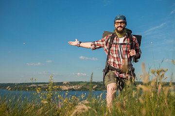 Image showing Young caucasian man with backpack standing on the top of hill