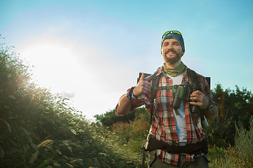 Image showing Young caucasian man with backpack walking on a green meadow