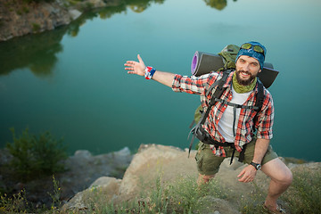 Image showing Young caucasian man with backpack standing on the top of hill