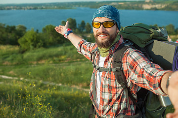 Image showing Young caucasian man with backpack standing on the top of hill