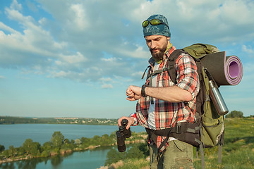 Image showing Young caucasian man with backpack standing on the top of hill