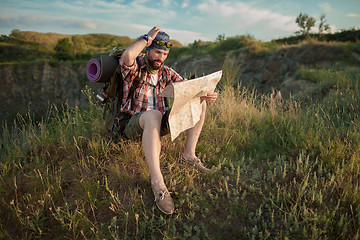 Image showing Young caucasian man with backpack sitting on the top of hill