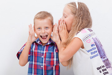 Image showing Teenage girl whispering in the ear of a secret teen boys on white  background