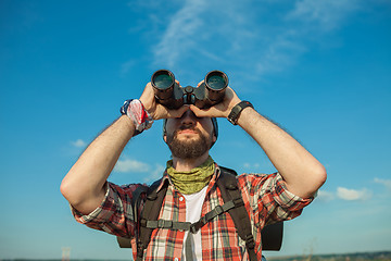 Image showing Young caucasian man with backpack standing on the top of hill