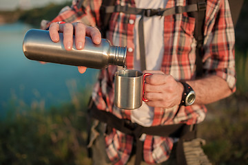 Image showing Young caucasian man with backpack resting and drinking water