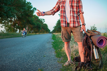 Image showing Young caucasian tourist hitchhiking along a road.