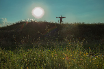 Image showing Young caucasian man with backpack walking on a green meadow