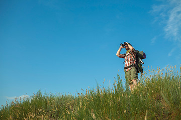 Image showing Young caucasian man with backpack standing on the top of hill