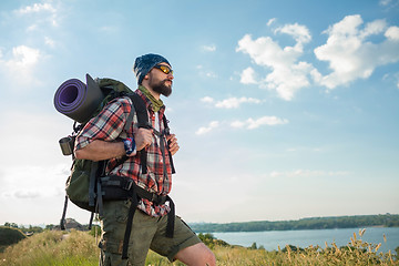 Image showing Young caucasian man with backpack standing on the top of hill