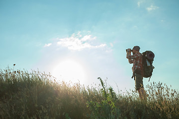 Image showing Young caucasian man with backpack standing on the top of hill