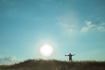 Image showing Young caucasian man with backpack walking on a green meadow