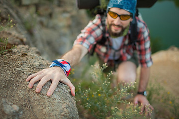 Image showing Young caucasian man with backpack rising on the rock