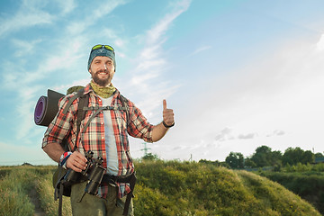 Image showing Young caucasian man with backpack standing on the top of hill