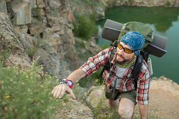 Image showing Young caucasian man with backpack climbing the rock