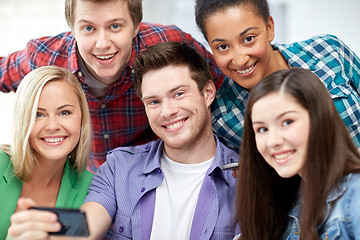 Image showing group of happy students with smartphone at school