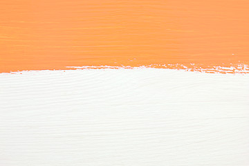 Image showing Stripe of orange paint over white wooden background