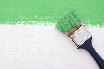 Image showing Stripe of green paint with a paintbrush on white