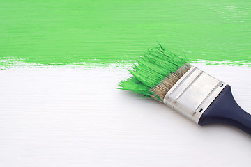 Image showing Paintbrush with green paint, painting over white board