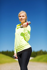 Image showing sporty woman with light dumbbells outdoors