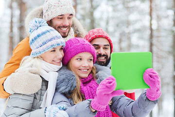 Image showing smiling friends with tablet pc in winter forest