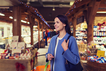 Image showing happy young woman with food basket in market