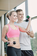 Image showing smiling young woman with personal trainer in gym