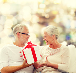 Image showing happy senior couple with gift box at home