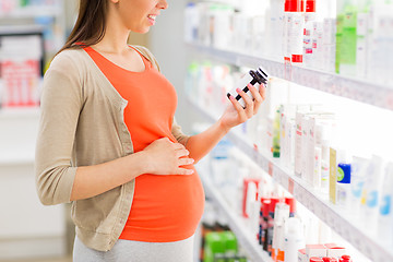 Image showing happy pregnant woman with medication at pharmacy