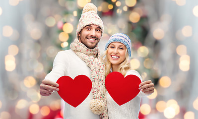 Image showing smiling couple in winter clothes with red hearts