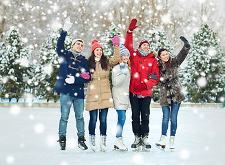 Image showing happy friends ice skating on rink outdoors