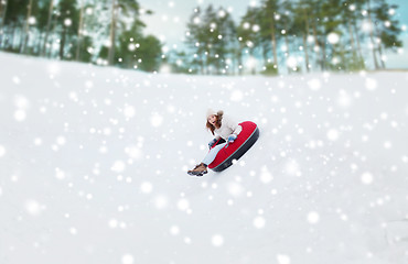 Image showing happy teenage girl sliding down on snow tube