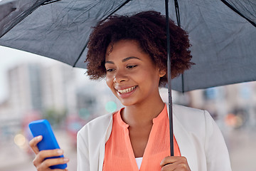 Image showing businesswoman with umbrella texting on smartphone