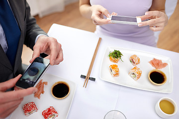 Image showing close up of couple with smartphones at restaurant