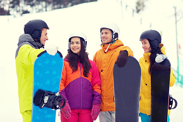 Image showing happy friends in helmets with snowboards talking