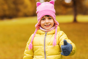 Image showing happy little girl showing thumbs up outdoors