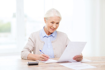 Image showing senior woman with papers and calculator at home