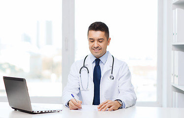 Image showing smiling male doctor with laptop in medical office