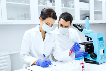 Image showing scientists with clipboard and microscope in lab