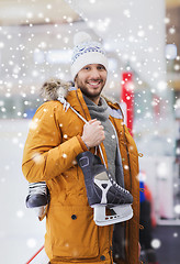 Image showing happy young man with ice-skates on skating rink