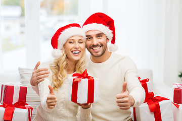 Image showing happy couple with christmas gifts and thumbs up