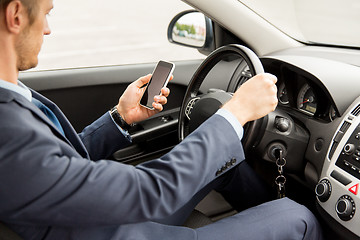 Image showing close up of man with smartphone driving car