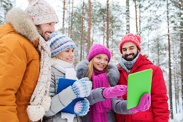 Image showing smiling friends with tablet pc in winter forest