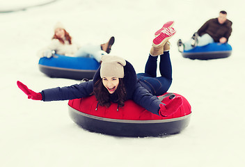 Image showing group of happy friends sliding down on snow tubes