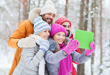 Image showing smiling friends with tablet pc in winter forest